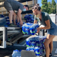 Volunteers and Multnomah County employees unload cases of water to supply a 24-hour cooling center set up in Portland, Oregon on Wednesday, Aug. 11, 2021.
